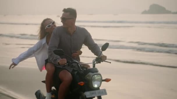 日出时 这对优雅的夫妇骑摩托车沿着海滨散步 内框安装从自行车到人 游客们在海滨驾驶租来的摩托车 女人拥抱着男人 用摩托车张开胳膊 — 图库视频影像