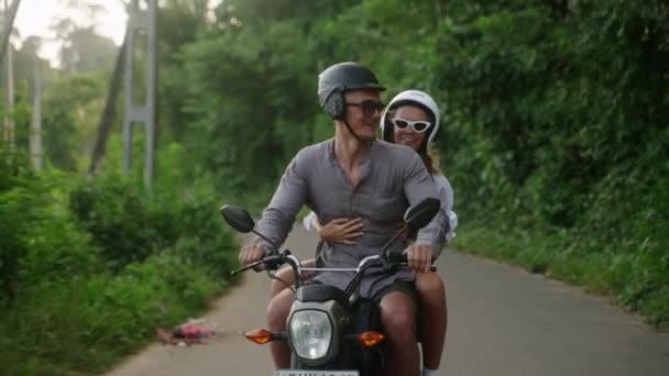 快乐的年轻夫妇骑摩托车旅行 两个快乐的情人在丛林中路上骑摩托车 女朋友笑了 点了手 游客在日落时驾驶摩托车 女人滑板车冒险 — 图库视频影像
