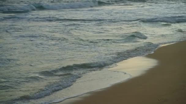 クリアブルーの海と教会の波が前景に砂浜に衝突します 夏の夕方にヤシの木と丘を持つ水とエキゾチックな熱帯島の石の岩 — ストック動画