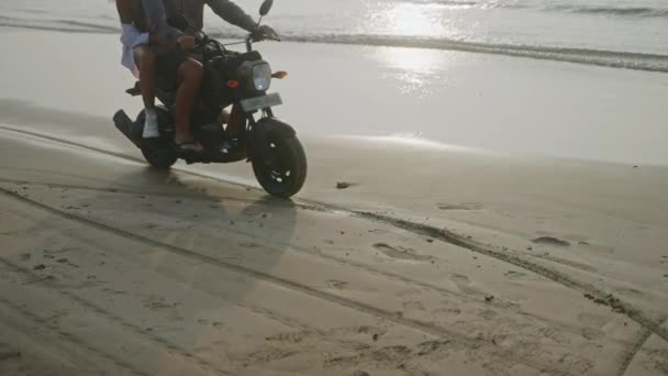 一对快乐的夫妇骑摩托车 日出时停在海滨 恋爱中的女人在海滨骑摩托车慢下来 戴着太阳镜的女孩 比基尼拥抱男朋友 和女朋友约会的家伙Slomo — 图库视频影像