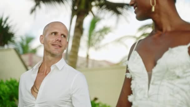 两名多民族男子在海上举行的同性合法婚姻聚会上行走 性感的新娘 恋爱中的新郎凝视着 新婚夫妇在海滩举行的婚礼上互相望着对方的眼睛笑着 — 图库视频影像