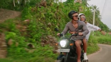 Motosiklet süren bir adam. Kadın erkek arkadaşına sarılıyor, bağırıyor, kollarını açıyor. Tropiklerde scooter 'a binmek. Aşık bir çift ormanda motosiklet sürüyor. Egzotik adada bisiklet yolculuğuna çıkan mutlu turistler.