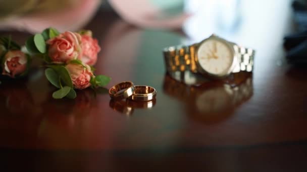 結婚式のための結婚式のグルームの付属品 テニス 金のリングおよび時計は結婚式のお祝いのために準備しました 高級ホテルの客室でウェディングアクセサリー 結婚式のロマンチックな詳細 クローズアップ — ストック動画