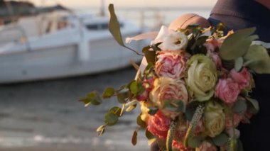 Düğün buketi pembe, beyaz güller ve okaliptüs gelinler gün batımında deniz kenarında. Yaz akşamları deniz suyundaki romantik fotoşopta taze çiçekler. Yakın plan..