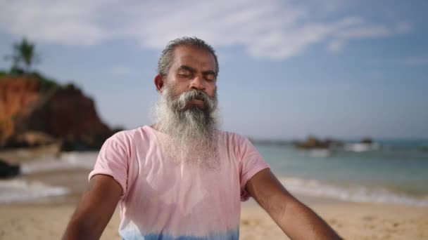 年长的灰胡子旅行者使用冥想练习和瑜伽来净化心灵 坐在热带岛屿上的荷花姿势 上了年纪 闭着眼睛 享受着退休生活 享受着棕榈树和大海 — 图库视频影像