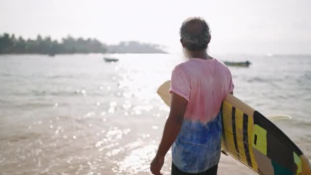 Senior Viajero Masculino Caminando Una Playa Con Tabla Surf Tiene — Vídeos de Stock
