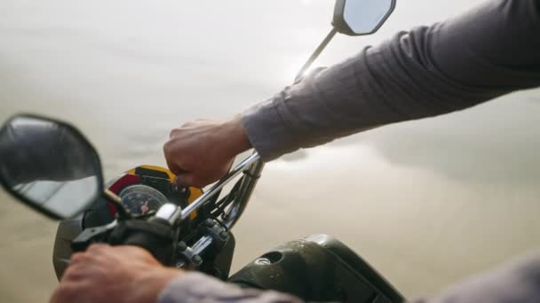 バイカーの手はオートバイの点火にキーを挿入し 海のビーチでモーターを起動します スピードメーター付きのバイクダッシュボード 男はスクーターを始め ドライブします クローズアップショット — ストック動画