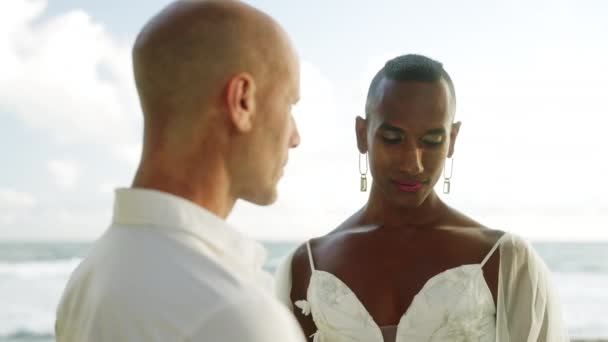 アンドロギーナス黒人 婚約後に海岸で愛情を持って見ている彼の婚約者 ゲイ多民族カップルは 結婚式のドレスでリングに置かれ スーツは熱帯の島でハネムーンを楽しんでいます — ストック動画