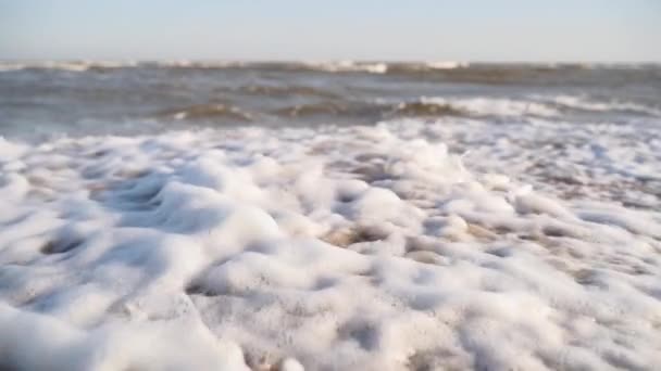 砂浜に衝突するシネマティックな白い泡立った波 水面のテクスチャの驚くべき海底の形 砂は日没時に波によって洗われる 海辺での夏休みを満喫してください クローズアップ — ストック動画