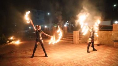 Geceleri yangın gösterisi. Dişi sanatçılar festivalde yanan meşaleyi açık havada çeviriyorlar. Ateş dansçıları akşam vakti alevler içinde sırıkları çeviriyorlar. Yangın sanatları ekibi turistler için mekanda hokkabazlık yapıyor..