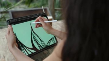 Kadın tasarımcının elleri, tropik adadaki kafede, palmiye ağaçlarında Stylus 'la resim çizer. Güzel bir kadın egzotik bir yerde açık havada çalışıyor. Genç tasarımcı illüstrasyonu. Yakın plan..