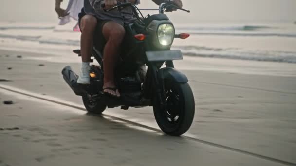 日出时 一对旅行夫妇骑摩托车沿着海滨游览 内框安装从自行车到人 游客们在海洋海岸线上驾驶租用的摩托车 女人拥抱着男人张开双臂骑摩托车 — 图库视频影像
