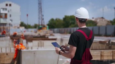 Hard Hat Holds Tablet Bilgisayar Giyen Profesyonel İnşaat İşçisinin Sırt Çekimi Modern Endüstriyel Üretim Tesisinde Duruyor.