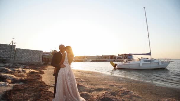 サンライズ 海のヨットでサンディビーチでハッピー新婚旅行 魅力的な花嫁は 感情を示し 日没で結婚式旅行に行きます 恋のカップル ロマンチックな写真撮影でポーズ — ストック動画