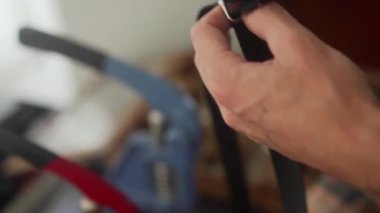 Profesyonel deri işçisine yakından bakın. Metal halkadan el çantasının kayışı. Atölyede çanta sapı yapma sürecinde olan erkek eller.