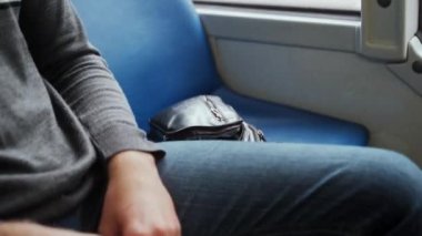 Genç erkek yolcu tramvayla seyahat ediyor, çantasından maskesini çıkarıp kuşkuyla takıyor. Günlük giysili bir adam otobüste oturuyor. Kişisel koruyucu ekipmanlarıyla. Covid 19 'dan korunmak için..