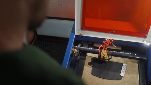 조각에 라벨을 적용하는 과정에서 레이저 기계를 제어하는 장인의 마스터는 작업장에서 — 비디오