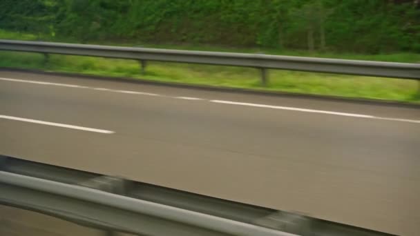 在快速移动的道路标记上 从车侧的窗口可以看到柏油路通过 乘公共汽车旅行 高速公路特写 冒险和运输的概念 绿色丛林森林背景 — 图库视频影像