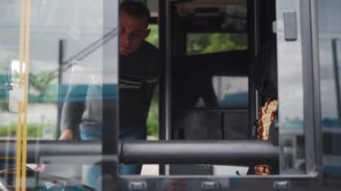 Profesyonel taşımacılık operatörü tramvaya biner, sürücü koltuğuna oturur ve ileri gider. Günlük kıyafetli genç adam işe başlamak için elektrikli araca biniyor..