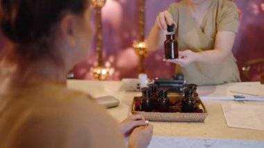 Yaşlı Asyalı kadın vücut bakımı prosedürlerini seçer. Otantik spa merkezinde aroma yağı kokar. Kıdemli çok ırklı kadın atmosferik geri çekilme merkezinde resepsiyonistle konuşuyor, tedavi programlarını seçiyor.
