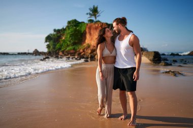 Sevecen erkek, kadın yalınayak yürür, okyanus dalgaları ayaklarını yıkar. Romantik çift gün batımında kumlu sahilde gezer. Çiftler deniz kenarından hoşlanırlar, kucaklaşırlar. Gezginler kıyı manzarasına, sükunete bayılırlar..