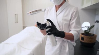 Uzman ürünleri estetik kliniğinde eldivenli ellere uygular. Güzellik uzmanı kaplıcada yüz bakımı için cilt temizleyici hazırlıyor. Cilt bakımı uzmanı yaşlanmayı önleme prosedürüne hazır. Temizle, hazırla, gençleştir.