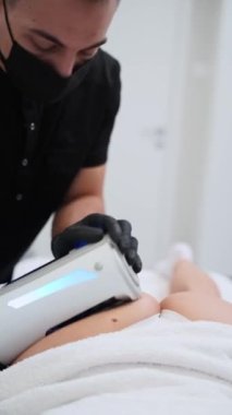 Daha pürüzsüz bir cilt için yenilikçi paten cihazı ile anti-selülit tedavisi. Profesyonel klinikte hastaların bacaklarına sonosfer terapi masajı yapıyor. Güzellik, sağlık, müdahalesiz prosedür konsepti.