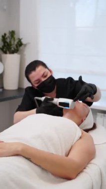 Yenilenme, kadın müşteride deri sıkılaştırma tedavisi. Güzellik uzmanı estetik kliniğinde sonosfer terapi ekipmanlarıyla yaşlanma karşıtı yüz masajı yapıyor. Uzman cilt bakım rutini.