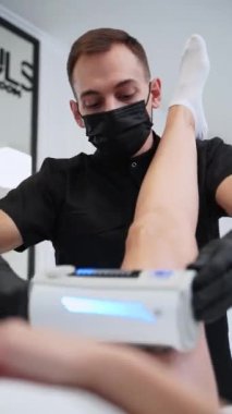 Deri sıkılaştırma için özel ekipmanlı anti-selülit tedavisi güzellik merkezinde vücut hatları oluşturma. Maskeli profesyonel modern klinikte hastaların bacakları üzerinde nihai terapi uyguluyor..