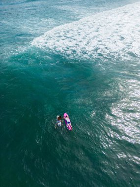 İHA çekimleri, açık turkuaz okyanusta sörfçüleri yakalıyor, tatil, macera sporları, sörf inzivaları ve egzotik doğa keşifleri için canlı kıyı manzaraları yakalıyor..
