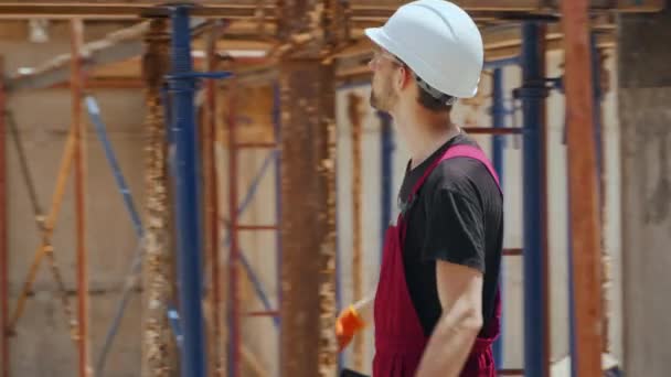 专业建筑工人头戴硬帽行走在建筑工地的整体框架结构中检查水平模板的侧拍 — 图库视频影像