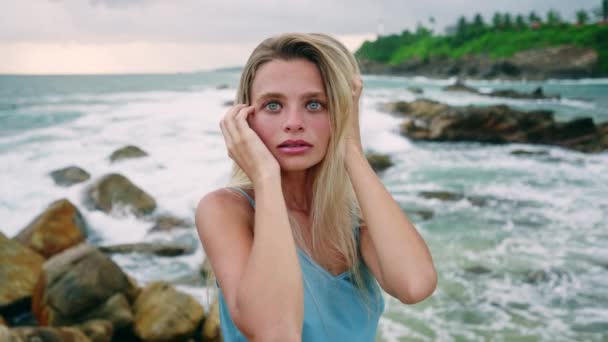 宁静的女性喜欢大自然 海风轻轻吹拂着头发 穿着蓝色衣服的女人站在悬崖上 波浪在下面的岩石上颠簸 沉思的心情在海洋中 孤独的时刻 — 图库视频影像