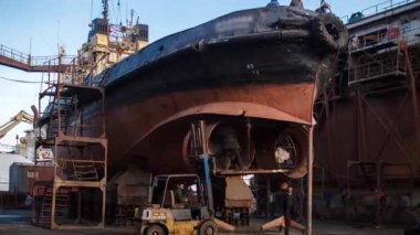 İşçiler tersanedeki yüzen rıhtımda eski bir gemiyi tamir ediyorlar. Gemi pervanesi onarımı. Zaman Uygulaması