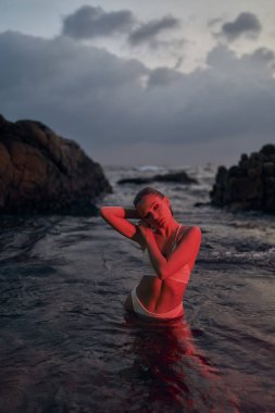 Zarif bir kadın, okyanustaki eğlence ve refahı sembolize eden, kırmızı ışıkla aydınlatılmış, huzurlu bir akşam yemeğinden zevk alır..