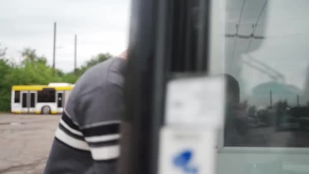 专业的运输商走到无轨电车前 上车后就坐在司机的座位上 身着休闲装的年轻人正赶往电动汽车上下班 — 图库视频影像