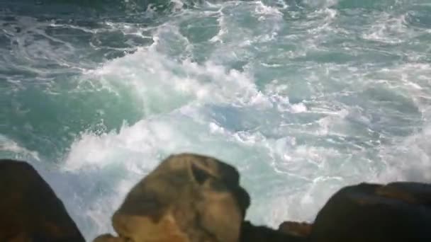 从悬崖顶上俯瞰着动态的海洋 岩石承受着无休止的汹涌 绿松石浪落在崎岖的海岸上 未经驯服的大海的能量 溅向海岸的水花 空气中喷出的刺鼻的浪花 原始的海洋场景 — 图库视频影像