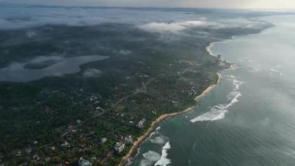 空中ハイパーラプス映像は 緑豊かな森林 原始のビーチ ターコイズ海の近くのダイナミックな日光の遷移を示す牧草地の海岸線の上を移動します — ストック動画