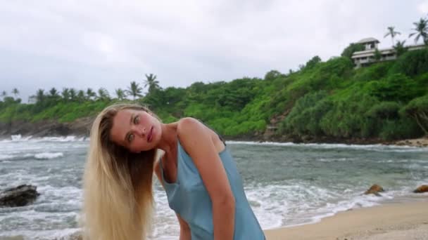 漂亮的模型展示了海上闪亮的锁 金发女子在热带海滩背景下飘扬长发 有天然海洋背景的护发素 健康的发型 沿海生活方式 — 图库视频影像