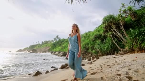 时尚模特走海路 热带背景 穿着蓝色衣服的优雅女人在沙滩上漫步 奢华的旅游生活 宁静的假期 高端度假服装展示 夏季收藏品展示 — 图库视频影像