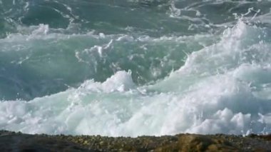 Doğanın gücünü gösteren kıyı manzarası. Sert deniz dalgaları kayalık kıyılara çarpıyor, püskürtüyor. Okyanus suyu köpürüyor, karaya vuruyor. Deniz erozyonu, doğal güçler iş başında. Çalkantılı gelgit, köpük.