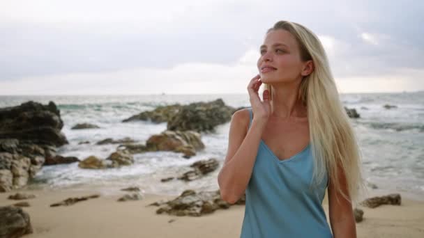 金发姑娘喜欢宁静的海滩落日 柔和的海浪拍打着岩石 女人在沙滩上漫步 蓝色的衣服在海风中飘扬 平静的热带度假场景 健康的旅行 — 图库视频影像