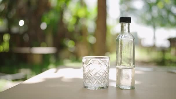 自然环境中的休息 环保容器中的清澈液体 水合物概念 透明的玻璃杯和装满水的瓶子放在室外木制桌子上 慢动作 — 图库视频影像