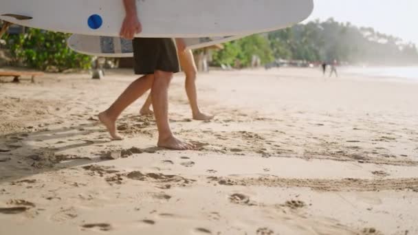 旅行者のカップルは 暖めるために砂浜にサーフボードを置きました 女はストレッチする前にレンタルボードを横たえました 観光客は海岸のトロピカルスポットでサーフィンセッションを開始します サーフキャンプ旅行 — ストック動画