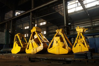 Fabrikanın içinde, sağlam mühendislik ve deniz lojistiğini sembolize eden, malzeme toplamaya hazır devasa mekanik istiridye kabukları var..