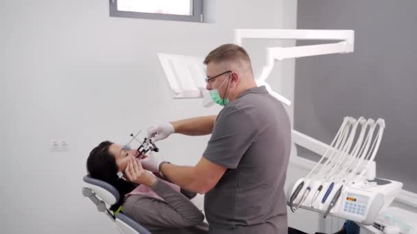 在现代牙科诊所 牙齿矫正师在妇女脸上安装牙面弓 牙科医生为女性患者安装了面部弓 以获得患者牙科治疗的信息 现代牙整形 — 图库视频影像