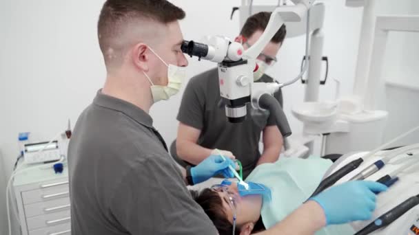 Dentysta Leczący Kanały Korzeniowe Mikroskopem Nowoczesnej Klinice Stomatologicznej Asystent Dentysty — Wideo stockowe