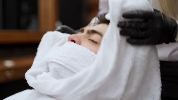 专业理发师为顾客准备剃须或护肤 男子在高档理发店接受热毛巾放松的面部治疗 豪华沙龙中男性的健康 美容美发 — 图库视频影像
