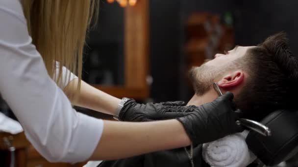 男子放松在时尚理发店的仪容 接受豪华胡子修剪 护理服务 专业的女理发师在高档理发店用直角剃须刀为男性客户剃须 — 图库视频影像