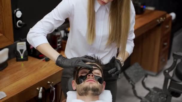 Trendig Manlig Hudvårdsrutin Frisörsalongen Frisören Applicerar Svart Mask Klienten För — Stockvideo
