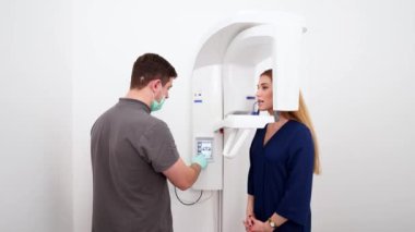 Erkek radyologlar diş röntgeni makinesiyle kadın hastanın diş röntgenini çekiyorlar. Dişçi lazer rehberiyle tarama projeksiyonunu ayarlar. Doktor, dişçi kliniğindeki kadın için röntgen çekiyor..